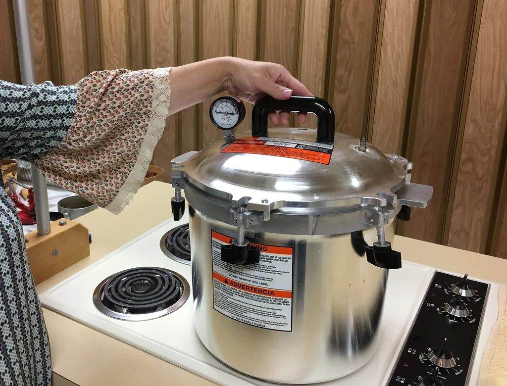 Person closing the lid of a pressure canner on an electric stove
