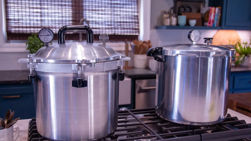 Two pressure canners with dial gauges on a kitchen stovetop