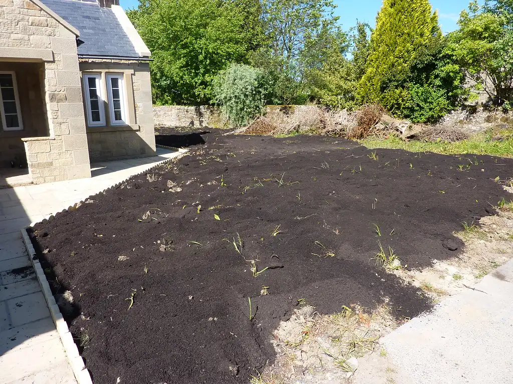 Dark compost spread in an even layer over a garden bed