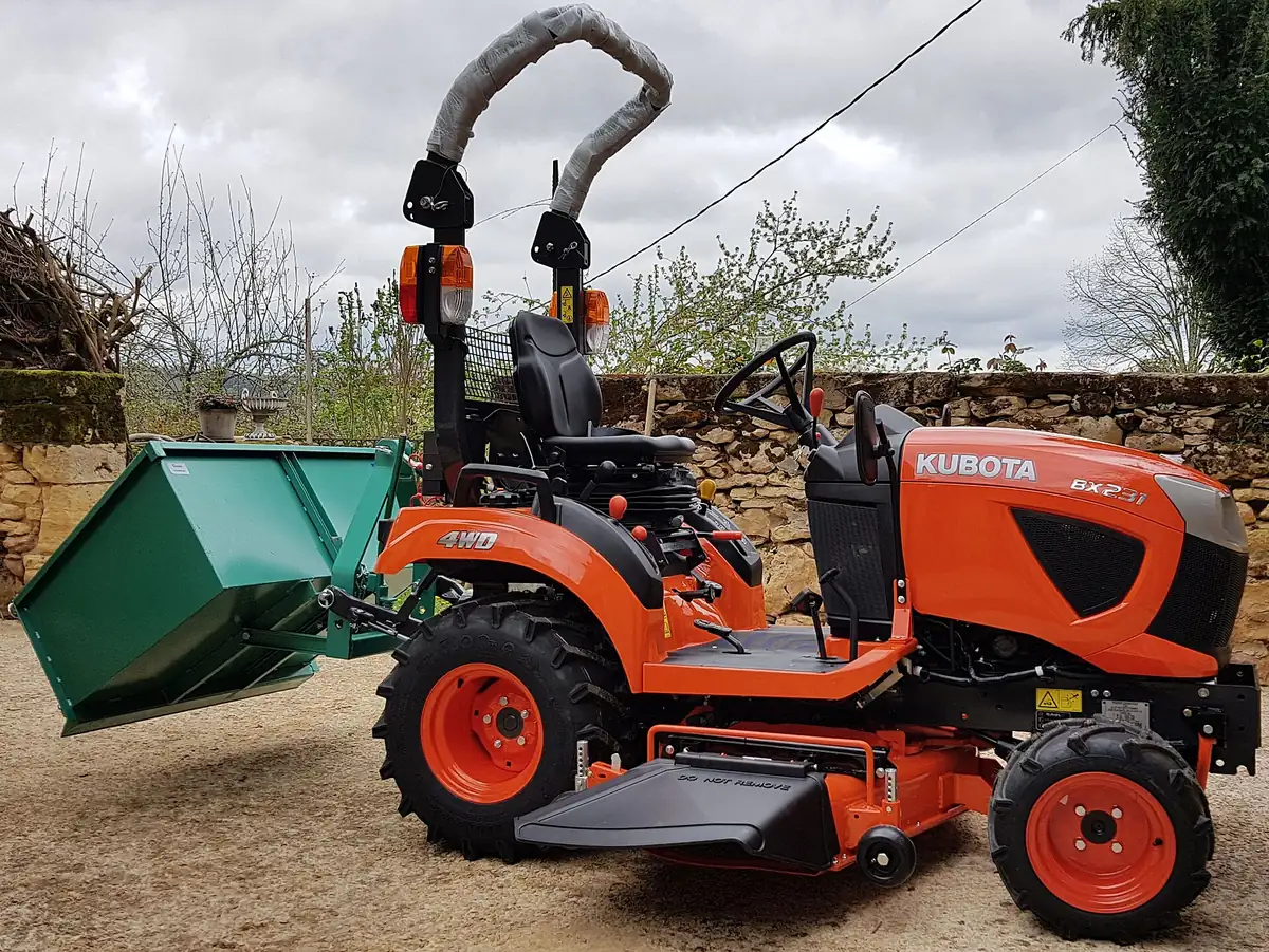 Orange Kubota BX sub-compact tractor with a mid-mount mower and a rear tipping box